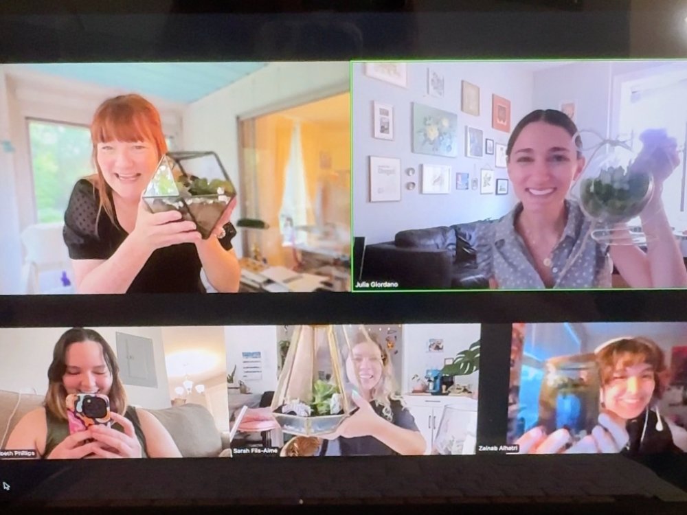 A screenshot of a Zoom meeting shows five women smiling and holding up plant terrariums