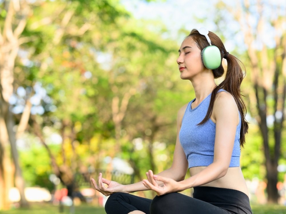 A woman meditating to reduce stress and increase creativity. A tip from the blog, How to Avoid Burnout, Writer’s Block, and Creative Slumps by Hummingbird Marketing Services.
