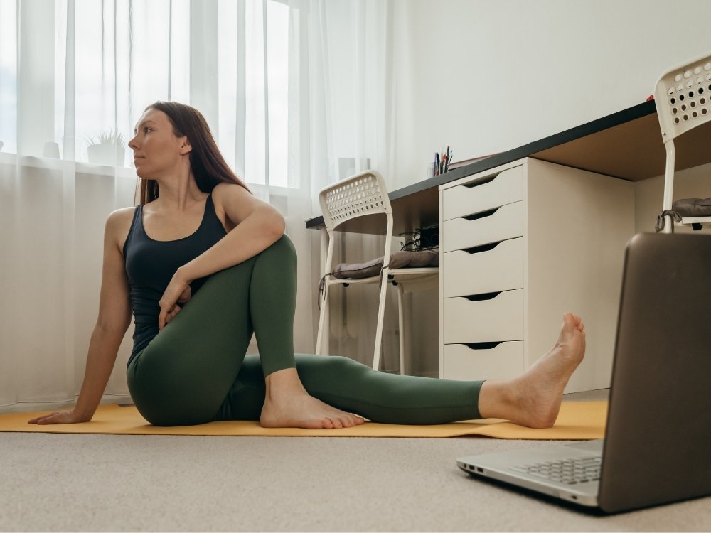 A woman stretching on yoga mat to depict incorporating movement into your work day. A tip from the blog, How to Avoid Burnout, Writer’s Block, and Creative Slumps by Hummingbird Marketing Services.