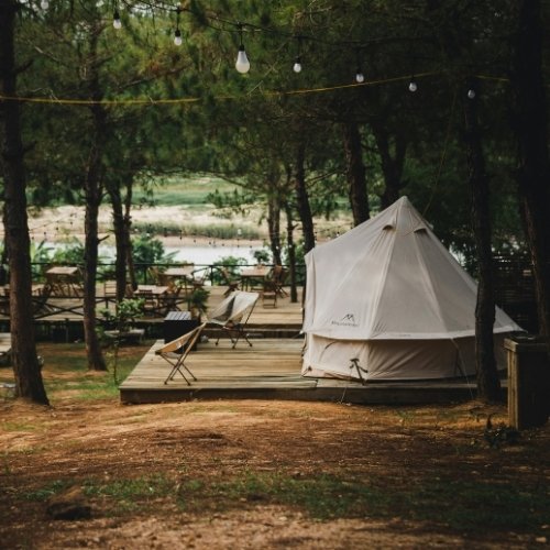 A wooden platform in a forest with a glamping tent and camping chairs as an example of a unique wedding venue.