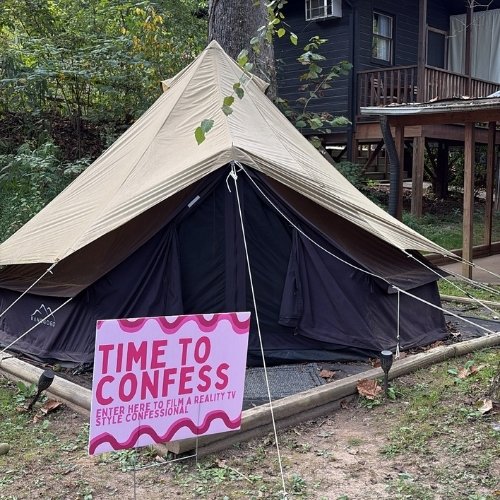 A hot pink sign that says "Time to Confess" outside of a camping tent.